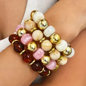 Nahaufnahme von gestapelten Boho-Armbändern mit goldenen und bunten glänzenden Perlen