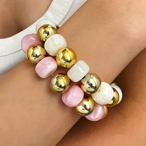 Nahaufnahme eines handgefertigten Boho-Armbands mit goldenen, rosa und weißen Marmorperlen.
