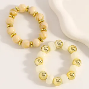 Nahaufnahme handgefertigter Boho-Perlenarmbänder mit Marmortextur und Goldakzenten.