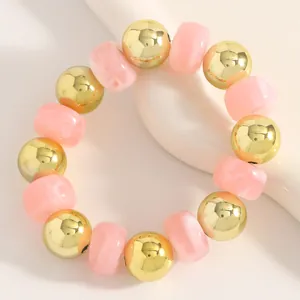 Detailansicht eines böhmischen Perlenarmbands mit glänzenden goldenen und rosa Perlen.