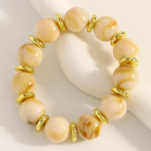 Nahaufnahme eines handgefertigten cremefarbenen Marmorperlen-Armbands mit Goldringen