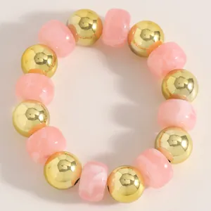 Nahaufnahme von rosa marmorierten Perlen und Goldkugeln an einem handgefertigten Armband