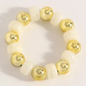 Detailansicht eines handgefertigten Perlenarmbands mit goldenen und milchweißen Perlen.