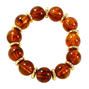 Nahaufnahme der bernsteinfarbenen Harzperlen und goldenen Metallelemente am Armband.
