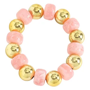 Detailansicht von rosa marmorierten Harzperlen und goldenen Kugeln am Boho-Armband