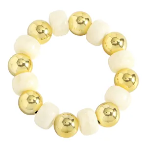 Makrodetail goldener Metallkugeln und cremeweißer Perlen auf einem handgemachten Armband