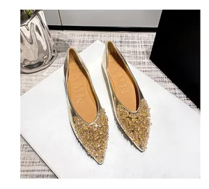 Detailaufnahme der eleganten goldenen spitzen Ballerinas mit luxuriösen Kristallen.