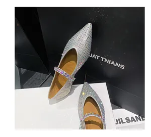 Nahaufnahme von silbernen spitzen Ballerinas mit Strasssteinen und Mary Jane-Riemen.