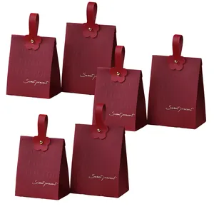 Detailansicht weinroter Hochzeit-Geschenktüten mit Ledergriffen und goldener Schrift