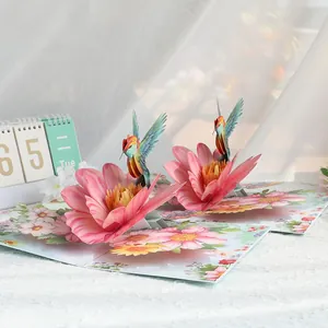 Detailed perspective of 3D pop-up hummingbird flower card on elegant white lace