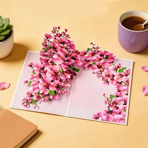 Vista detallada de una tarjeta 3D pop-up con esculturas de papel de orquídeas rosas.