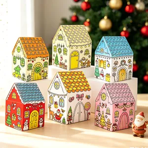 Set di sei scatole di caramelle natalizie colorate a forma di casa su un tavolo festivo.
