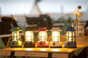 Five colorful retro camping lanterns glowing on a wooden table in an outdoor setting