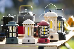 Array of colorful vintage camping lanterns on a wooden table outdoors.