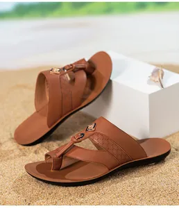 Vue détaillée de tongs élégantes en cuir marron pour hommes avec motifs imprimés sur sable