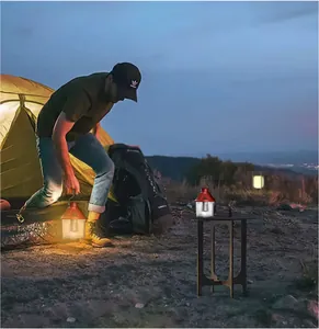 Red retro camping lantern illuminating an outdoor campsite at dusk near a tent