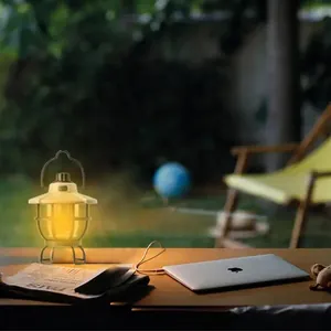 Portable retro style ambient camping lantern with warm yellow light on a wooden desk