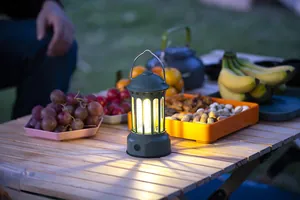 Close-up of a warm glowing retro camping lantern on a wooden picnic table at dusk