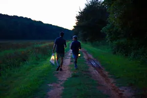 Dettaglio suggestivo di una lanterna da campeggio a LED vintage portata su un sentiero al crepuscolo