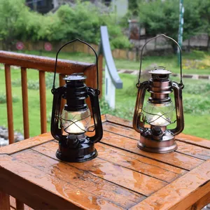 Ζευγάρι vintage LED φανάρια κάμπινγκ σε μαύρο και χάλκινο σε βρεγμένο ξύλινο τραπέζι