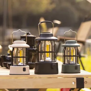 Vintage style LED camping lanterns in multiple colors displayed on a wooden table outdoors