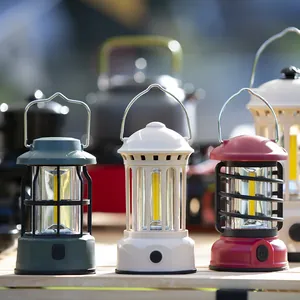 Three retro portable LED camping lanterns in green, white, and red on a wooden table.