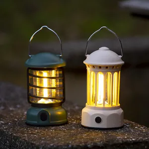 Two vintage-style LED camping lanterns in green and white glowing on a stone surface