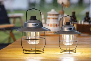Twee retro LED-kampeerlantaarns in verschillende maten op een houten tafel.
