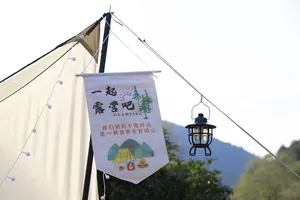 Vintage black camping lantern hanging outdoors near a tent with a decorative flag