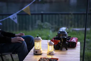 Warm ambient glow from retro LED camping lanterns on a wooden slatted table at dusk.