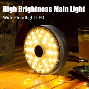 High-brightness circular LED camping light with warm yellow glow on outdoor wooden table