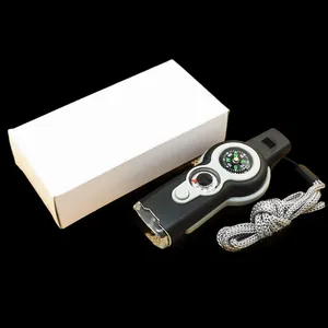 Detail der 7-in-1-Überlebenspfeife mit Kompass und LED-Licht neben der weißen Verpackung.