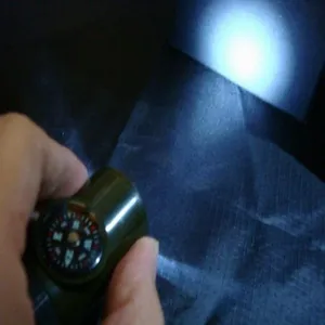 Detail of multi-functional survival whistle showing bright LED light beam and integrated compass