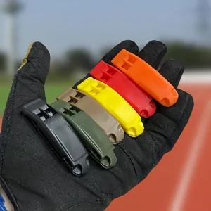 Sifflets de survie colorés à haute fréquence tenus dans un gant tactique noir solide