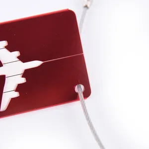Close-up view of a red aluminum luggage tag with airplane cutout and durable steel cable.