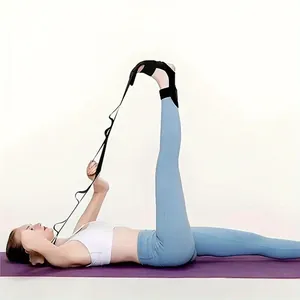 Detalle de una mujer usando una correa de yoga negra con bucles para estirar las piernas