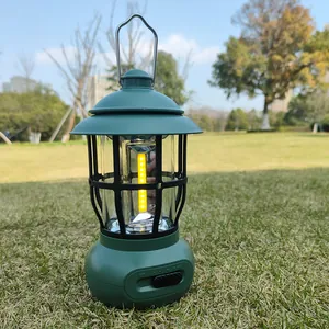 Vintage green LED camping lantern with warm COB light on a grassy field backdrop.