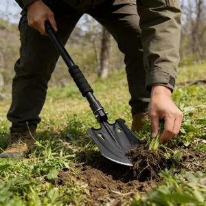 Foto d'azione di una pala tattica multifunzionale che scava nel terreno durante il campeggio.