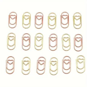 Righe di graffette metalliche a forma di cuore oro e oro rosa su sfondo bianco pulito