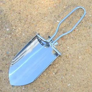 Dettaglio di una mini pala da giardino pieghevole in acciaio inox su fondo sabbioso.