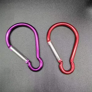 Detail of two bulb-shaped aluminum carabiners in vibrant purple and red finishes.
