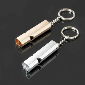 Detail view of gold and silver aluminum dual-tube high-frequency survival whistles.