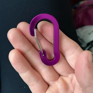 Nahaufnahme eines lila Aluminiumkarabiners in Birnenform, zur Skalierung in der Hand.