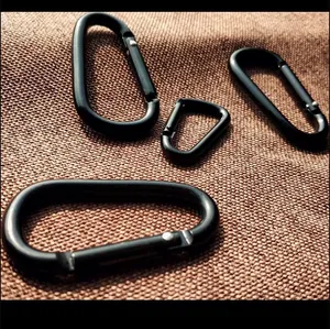 Various sizes of black aluminum D-shaped carabiners on a textured brown background