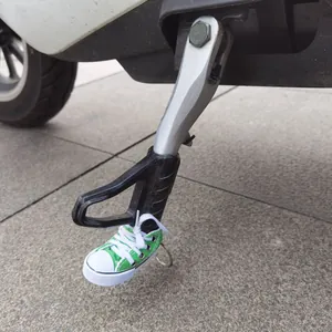 Mini green canvas shoe accessory used as a functional motorcycle kickstand cover decoration
