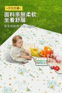 Bambino seduto su un tappetino da picnic impermeabile con motivi di animali