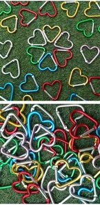 Detail view of colorful heart-shaped mini carabiners on green grass background