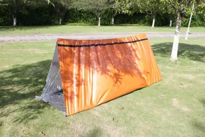 Emergency survival tent made of insulated PE material set up on grass outdoors.
