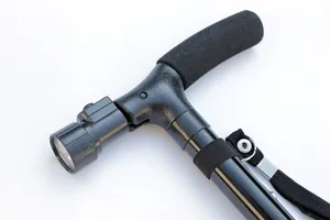 Dettaglio dell'impugnatura ergonomica e della luce LED su un bastone da passeggio nero per anziani