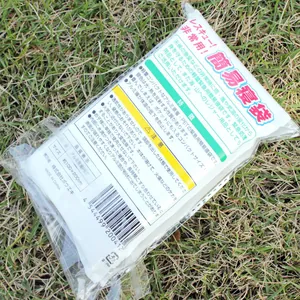 Close-up detail of a silver emergency sleeping bag in Japanese packaging on grass